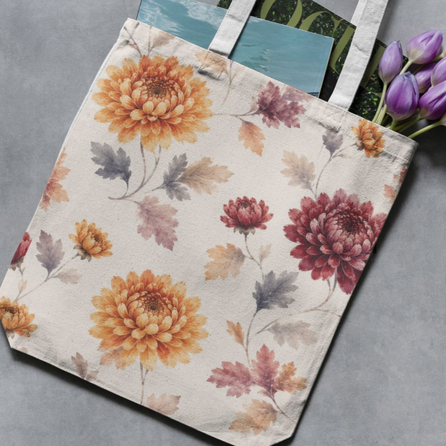 Autumn chrysanthemum floral pattern shown on a fabric tote bag, with large orange and burgundy flowers and softly painted grey, plum and ochre leaves.